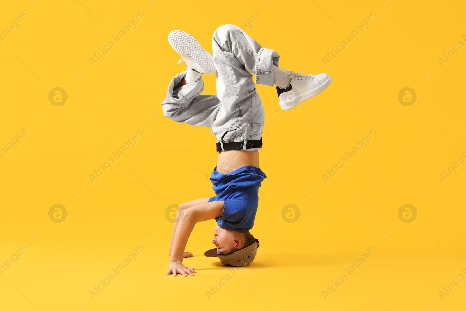 Boy in stylish clothes dancing on orange background Photo of Boy in stylish clothes dancing on orange background