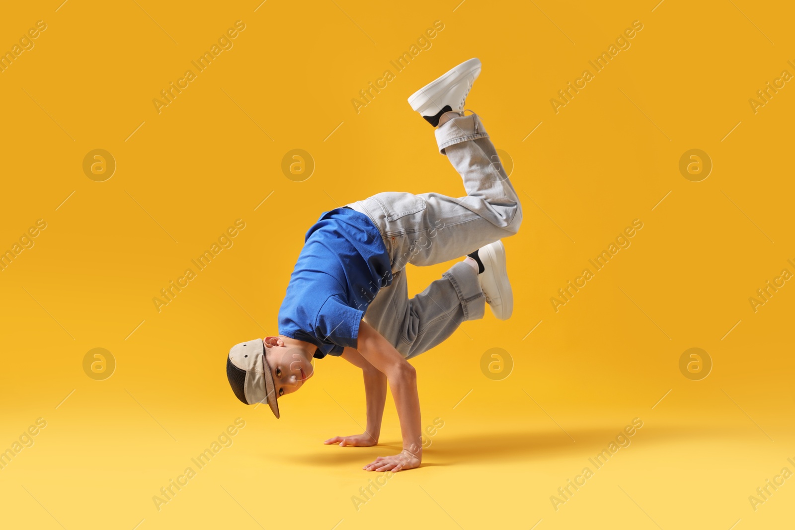 Boy in stylish clothes dancing on orange background Photo of Boy in stylish clothes dancing on orange background