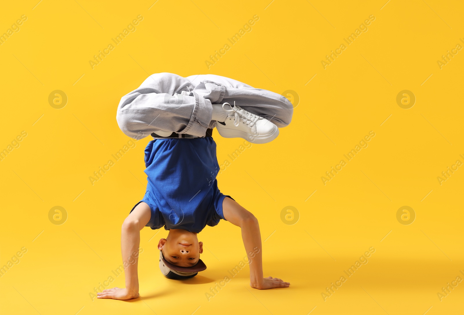 Boy in stylish clothes dancing on orange background, space for text Photo of Boy in stylish clothes dancing on orange background, space for text