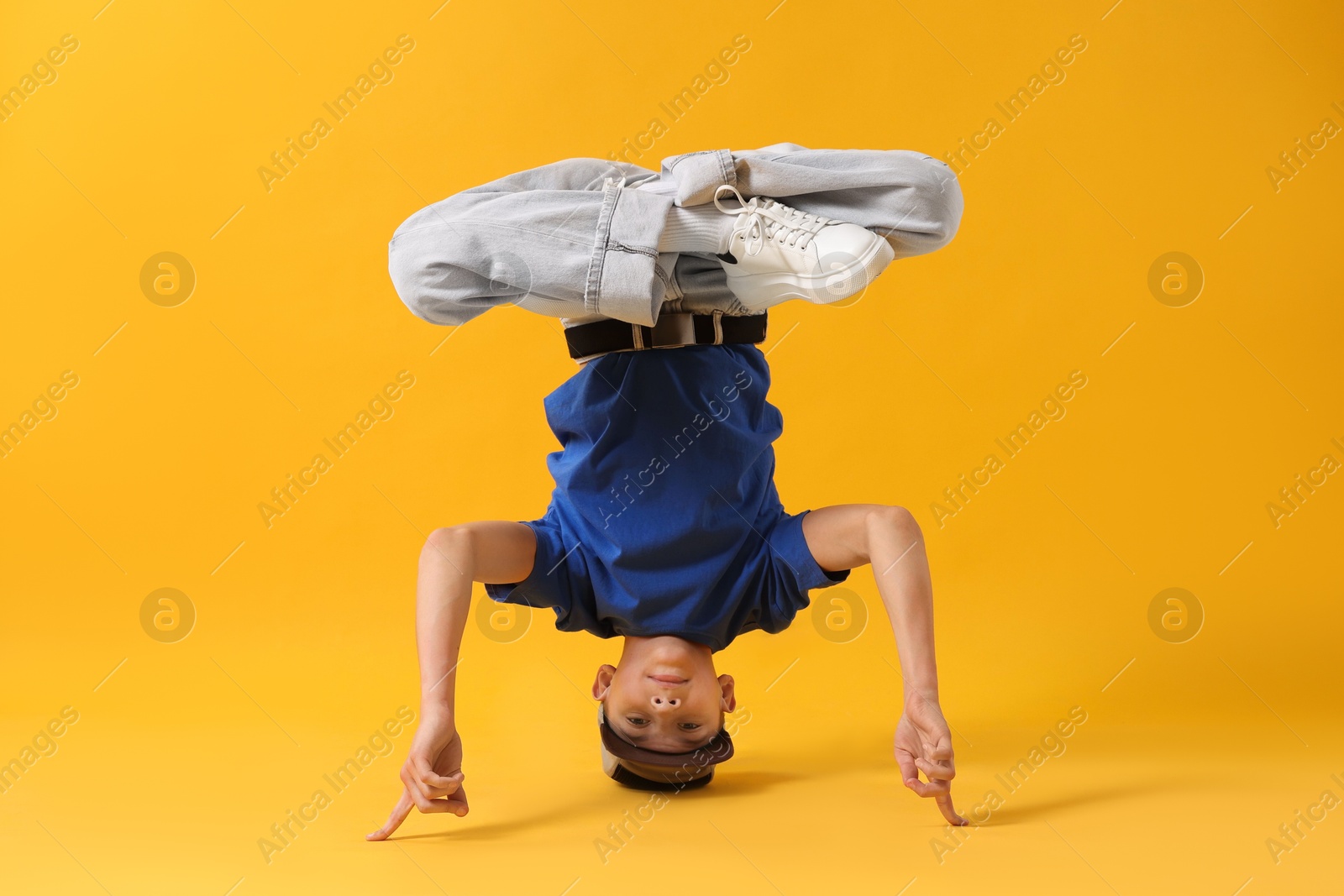 Boy in stylish clothes dancing on orange background Photo of Boy in stylish clothes dancing on orange background