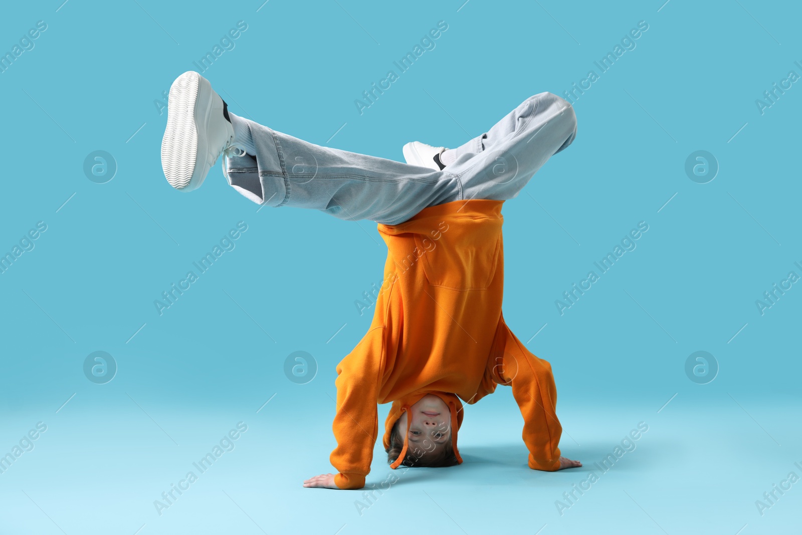 Boy in stylish clothes dancing on light blue background Photo of Boy in stylish clothes dancing on light blue background