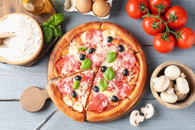 Photo of Tasty pizza and ingredients on grey wooden table, flat lay