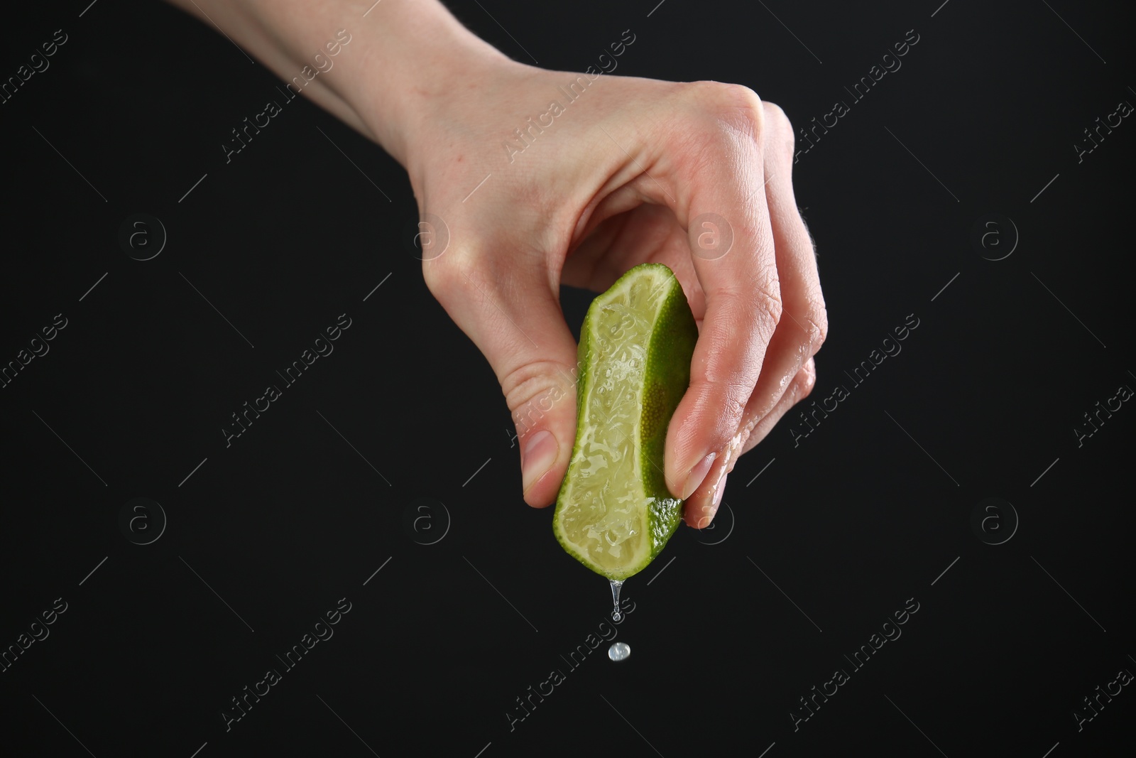 Woman squeezing lime on black background, closeup Photo of Woman squeezing lime on black background, closeup