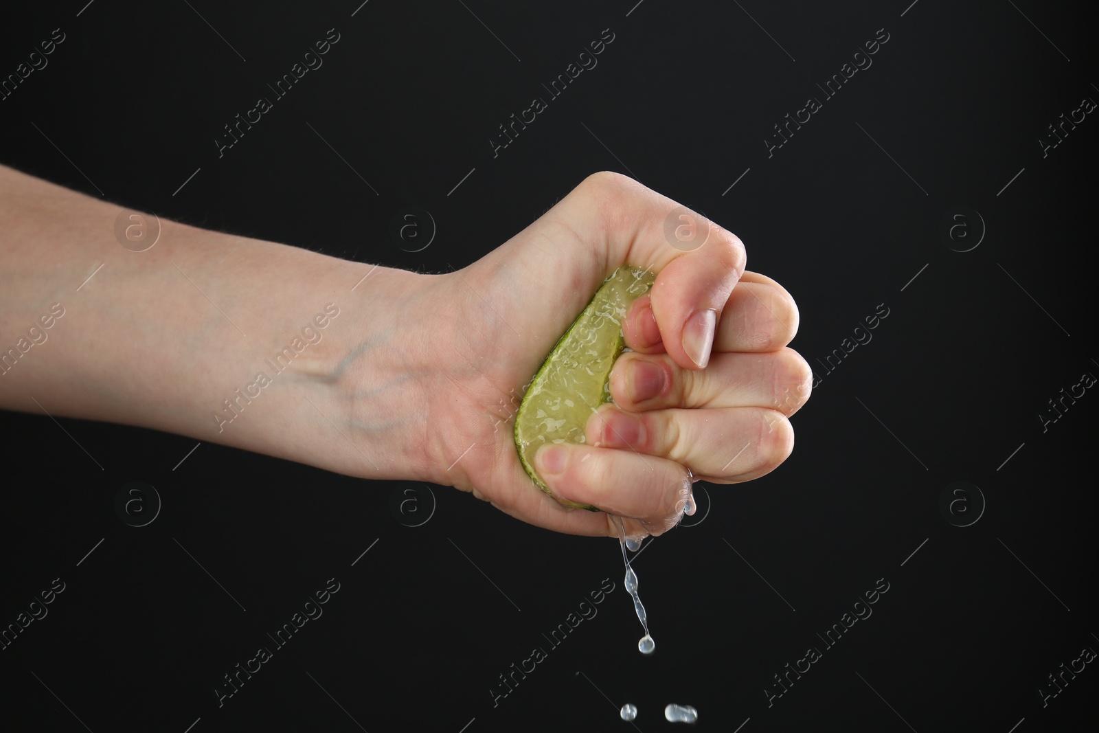 Woman squeezing lime on black background, closeup Photo of Woman squeezing lime on black background, closeup