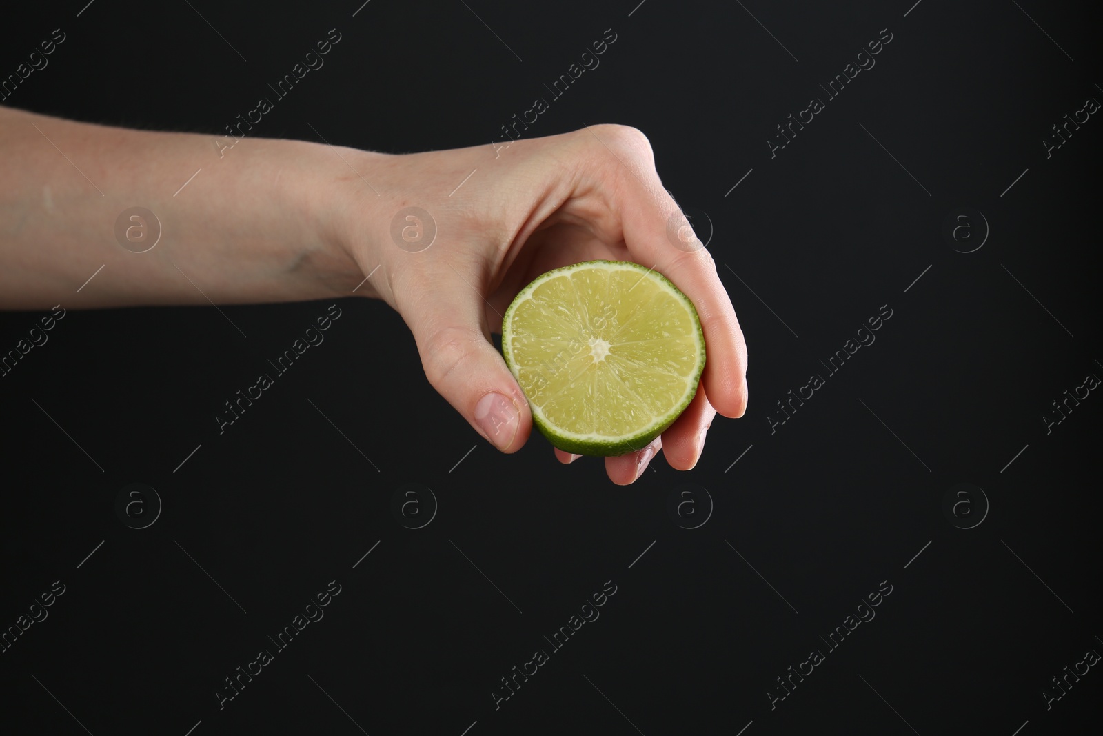 Woman squeezing lime on black background, closeup Photo of Woman squeezing lime on black background, closeup
