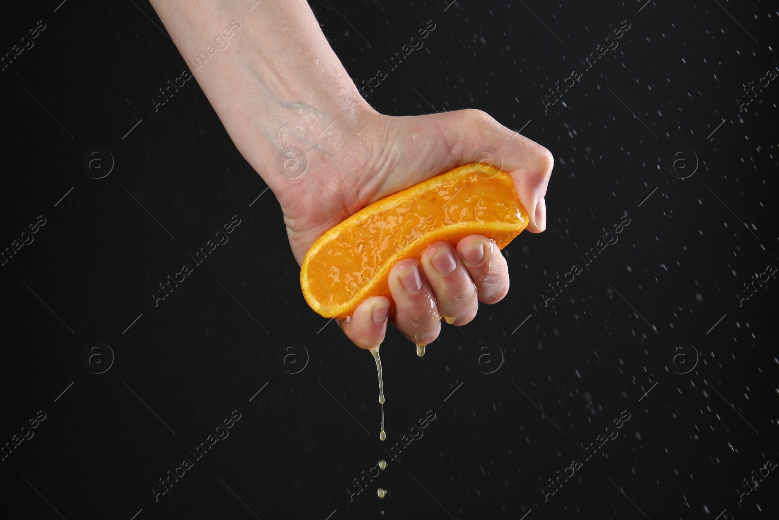Woman squeezing orange on black background, closeup Photo of Woman squeezing orange on black background, closeup