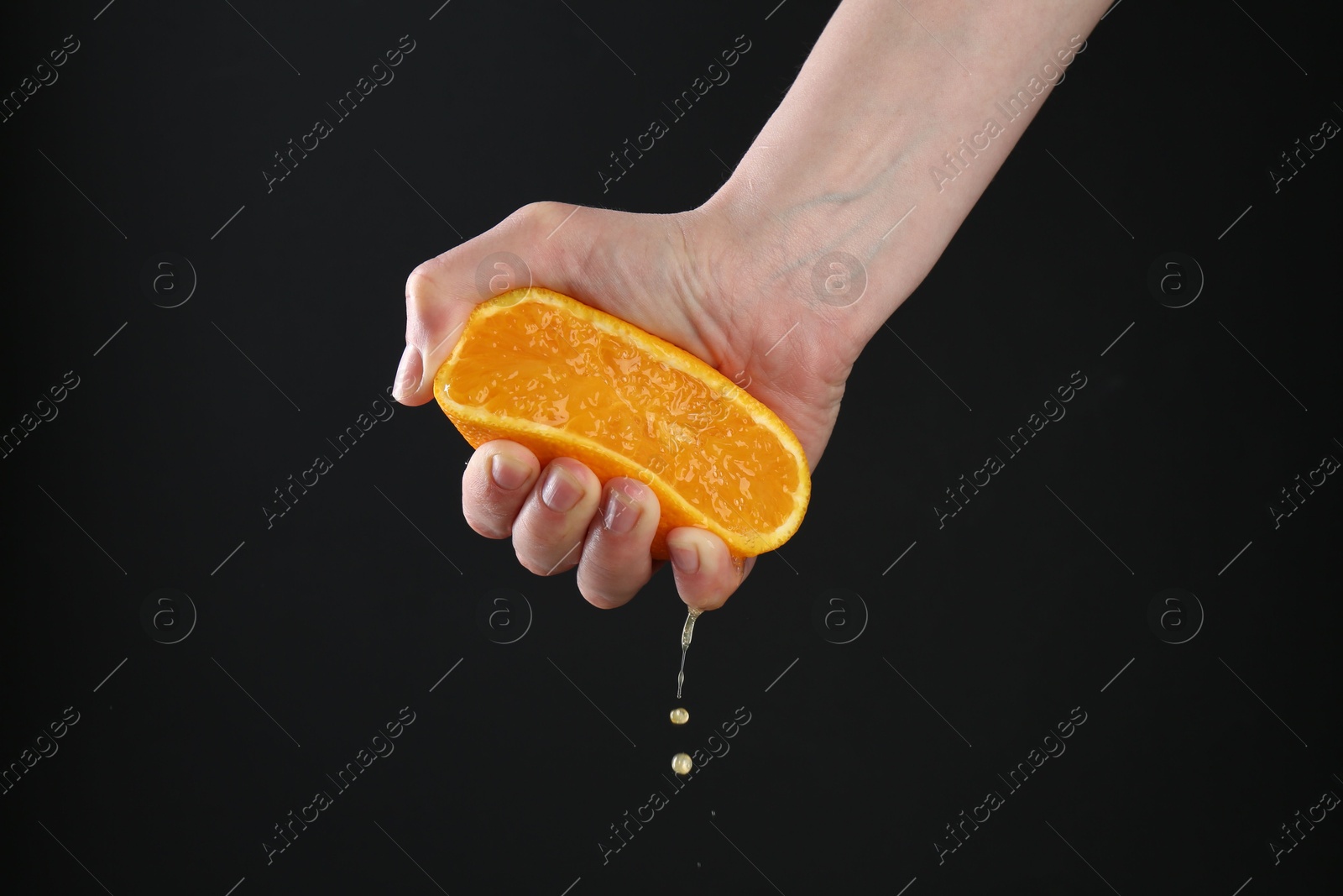 Woman squeezing orange on black background, closeup Photo of Woman squeezing orange on black background, closeup