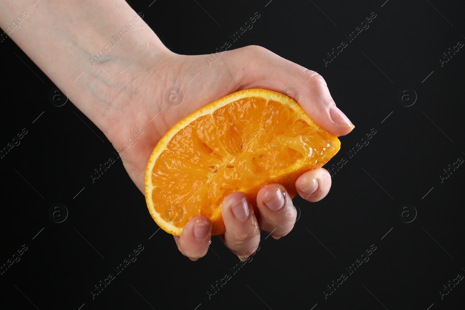 Woman squeezing orange on black background, closeup Photo of Woman squeezing orange on black background, closeup