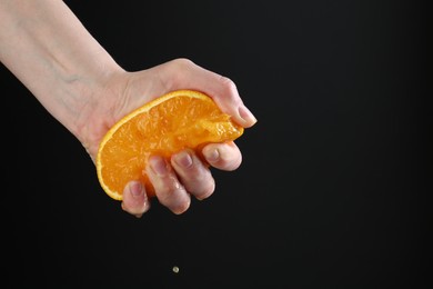 Photo of Woman squeezing orange on black background, closeup. Space for text