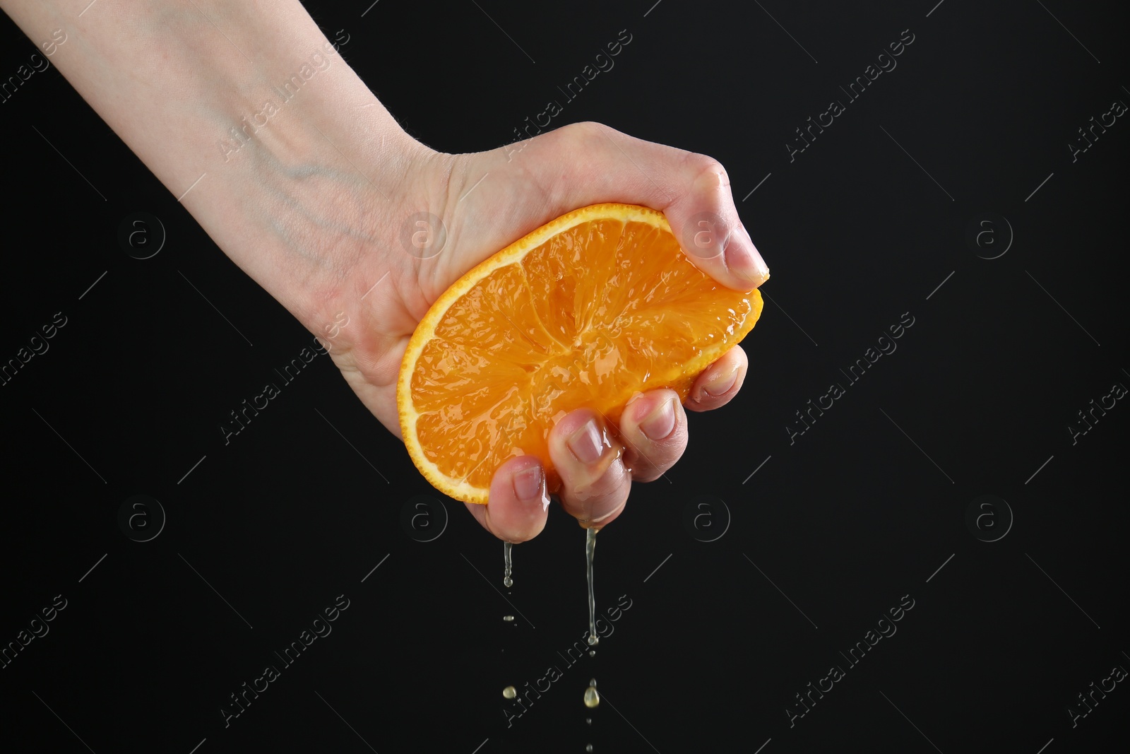Woman squeezing orange on black background, closeup Photo of Woman squeezing orange on black background, closeup