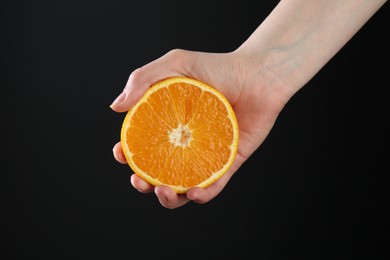 Photo of Woman with orange on black background, closeup
