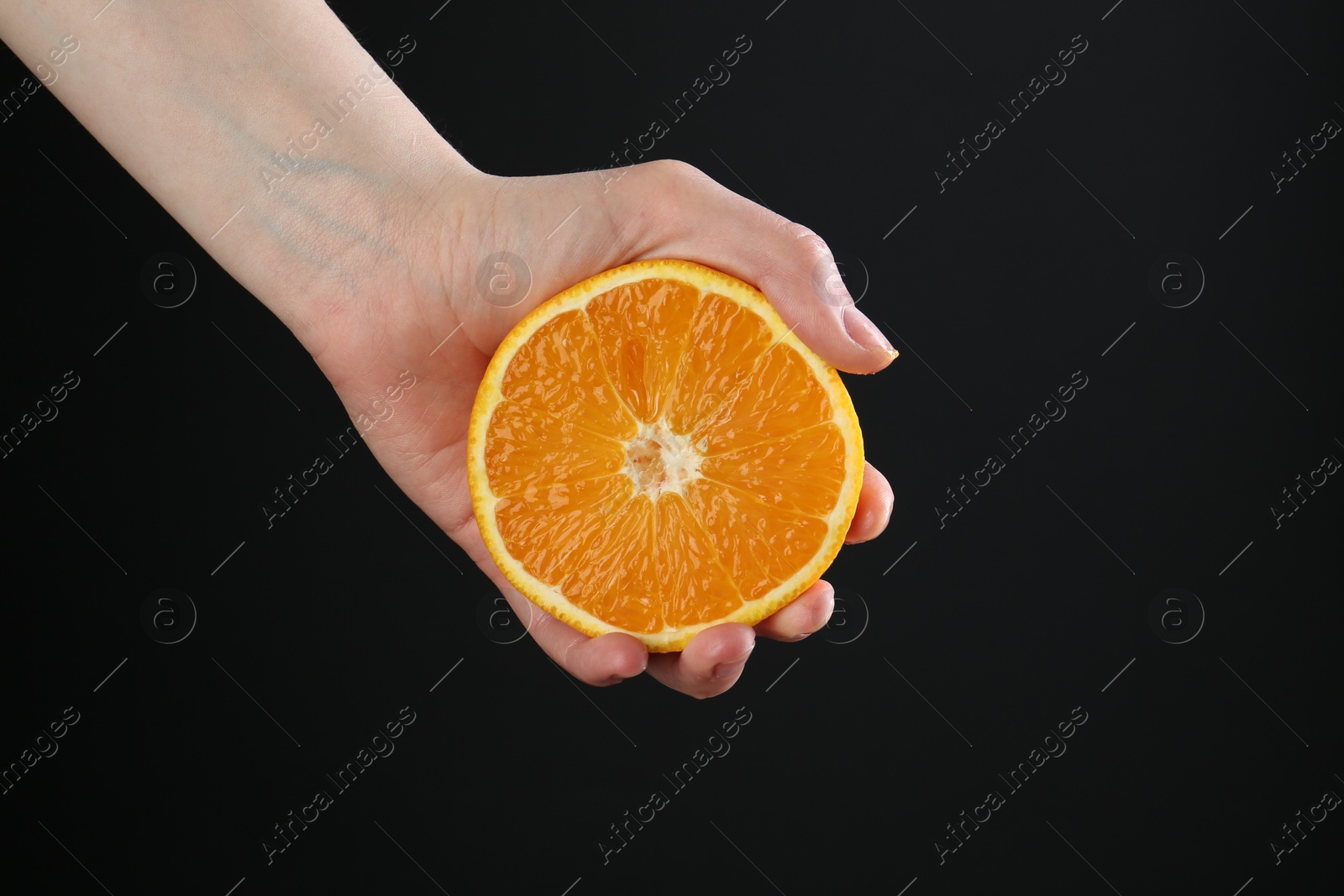 Woman with orange on black background, closeup Photo of Woman with orange on black background, closeup