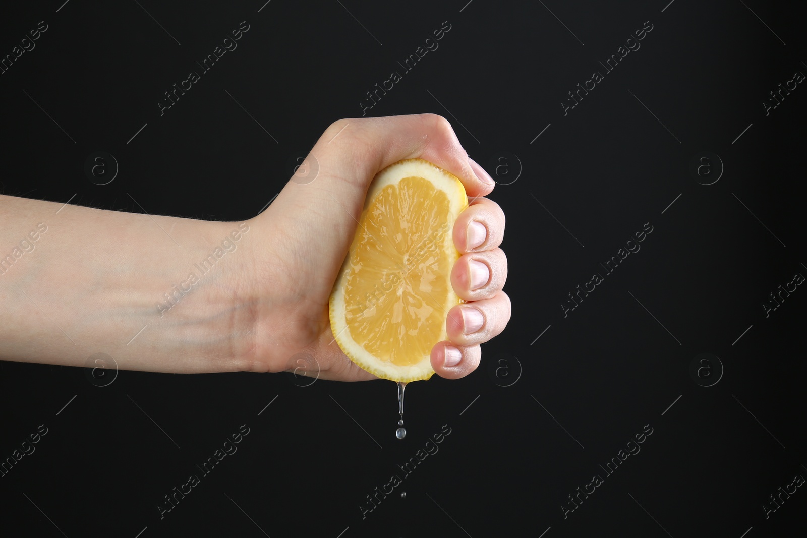 Woman squeezing lemon on black background, closeup Photo of Woman squeezing lemon on black background, closeup