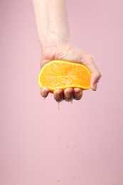 Photo of Woman squeezing orange on pink background, closeup. Space for text