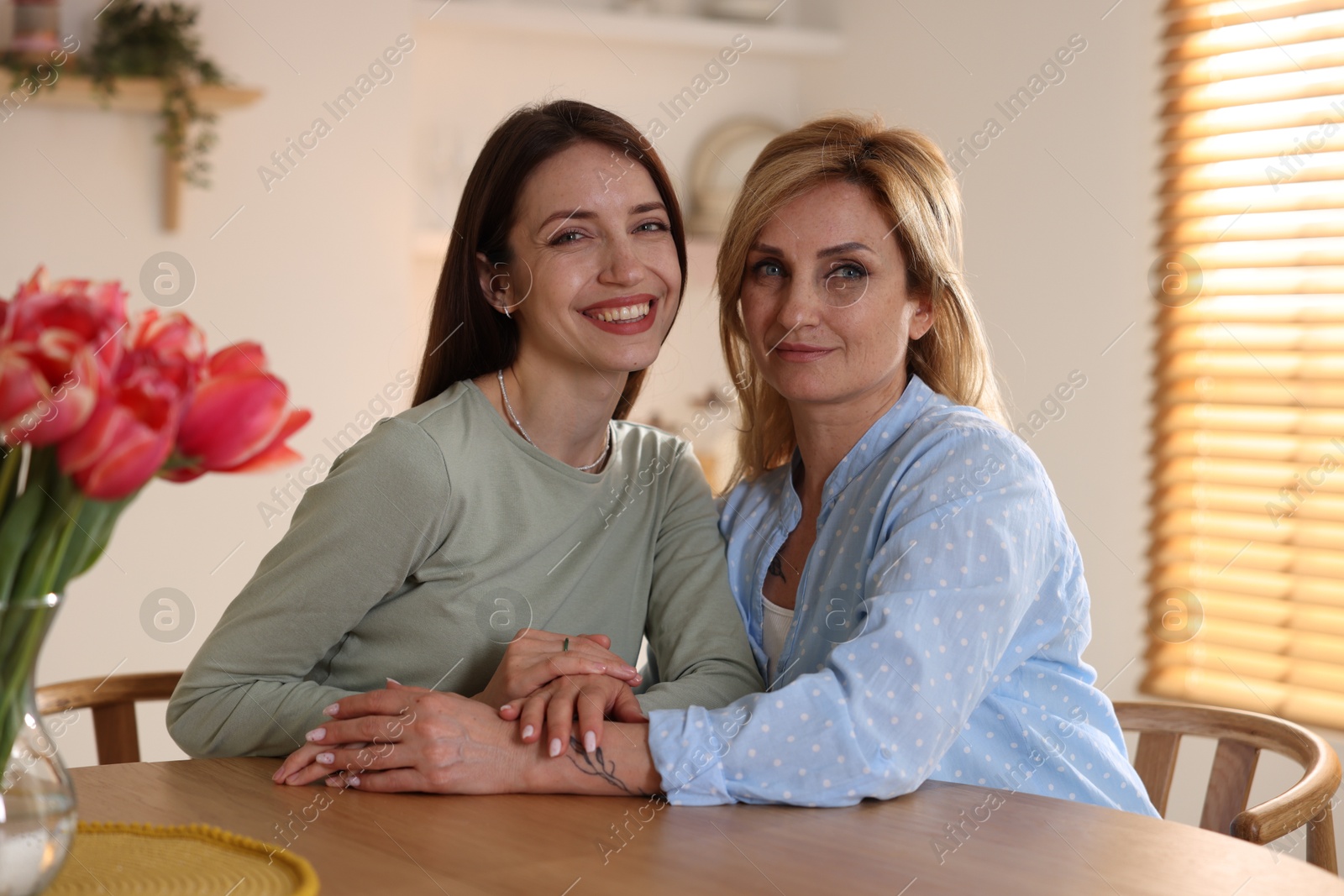 Beautiful mother and daughter at table indoors Photo of Beautiful mother and daughter at table indoors