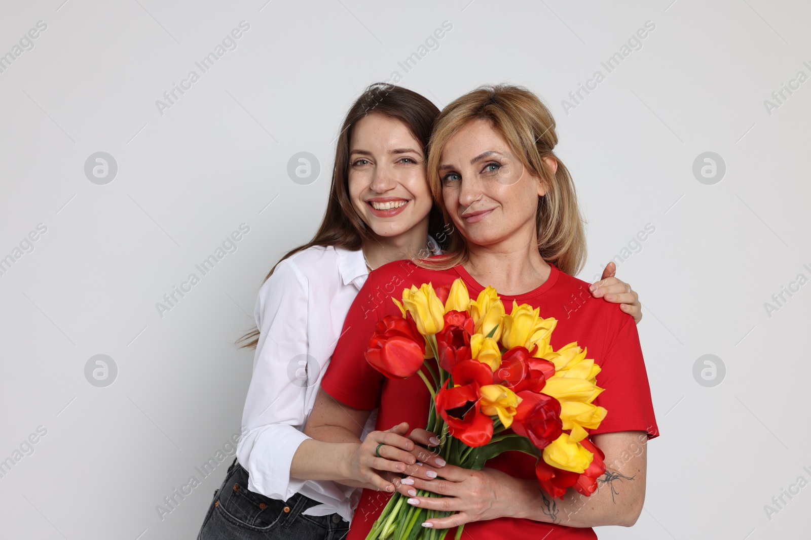Woman giving her mother flowers on white background Photo of Woman giving her mother flowers on white background