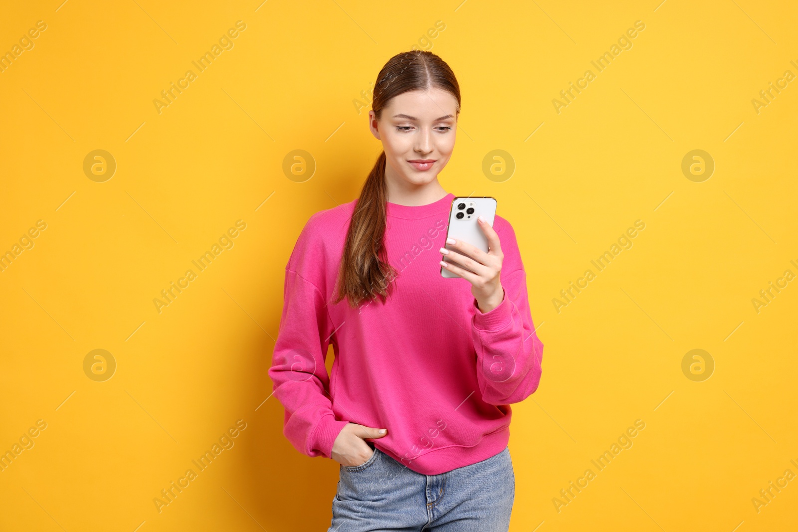 Photo of Teenage girl with smartphone on yellow background