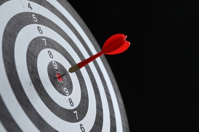 Photo of Targeting. Dart board with arrow on black background, closeup