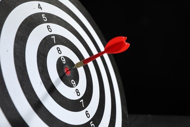 Photo of Targeting. Dart board with arrow on black background, closeup