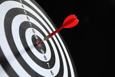 Photo of Targeting. Dart board with arrow on black background, closeup