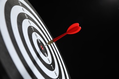 Photo of Targeting. Dart board with arrow on black background, closeup