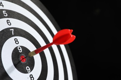 Photo of Targeting. Dart board with arrow on black background, closeup. Space for text