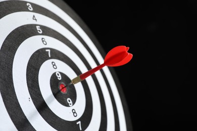 Photo of Targeting. Dart board with arrow on black background, closeup