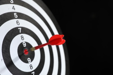 Photo of Targeting. Dart board with arrow on black background, closeup. Space for text
