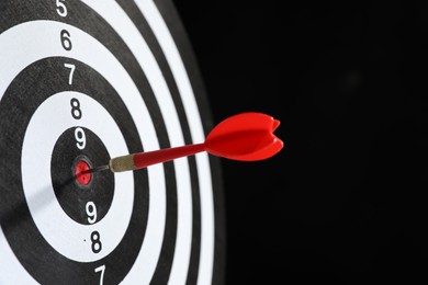 Photo of Targeting. Dart board with arrow on black background, closeup