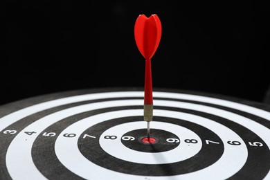 Photo of Targeting. Dart board with arrow on black background, closeup