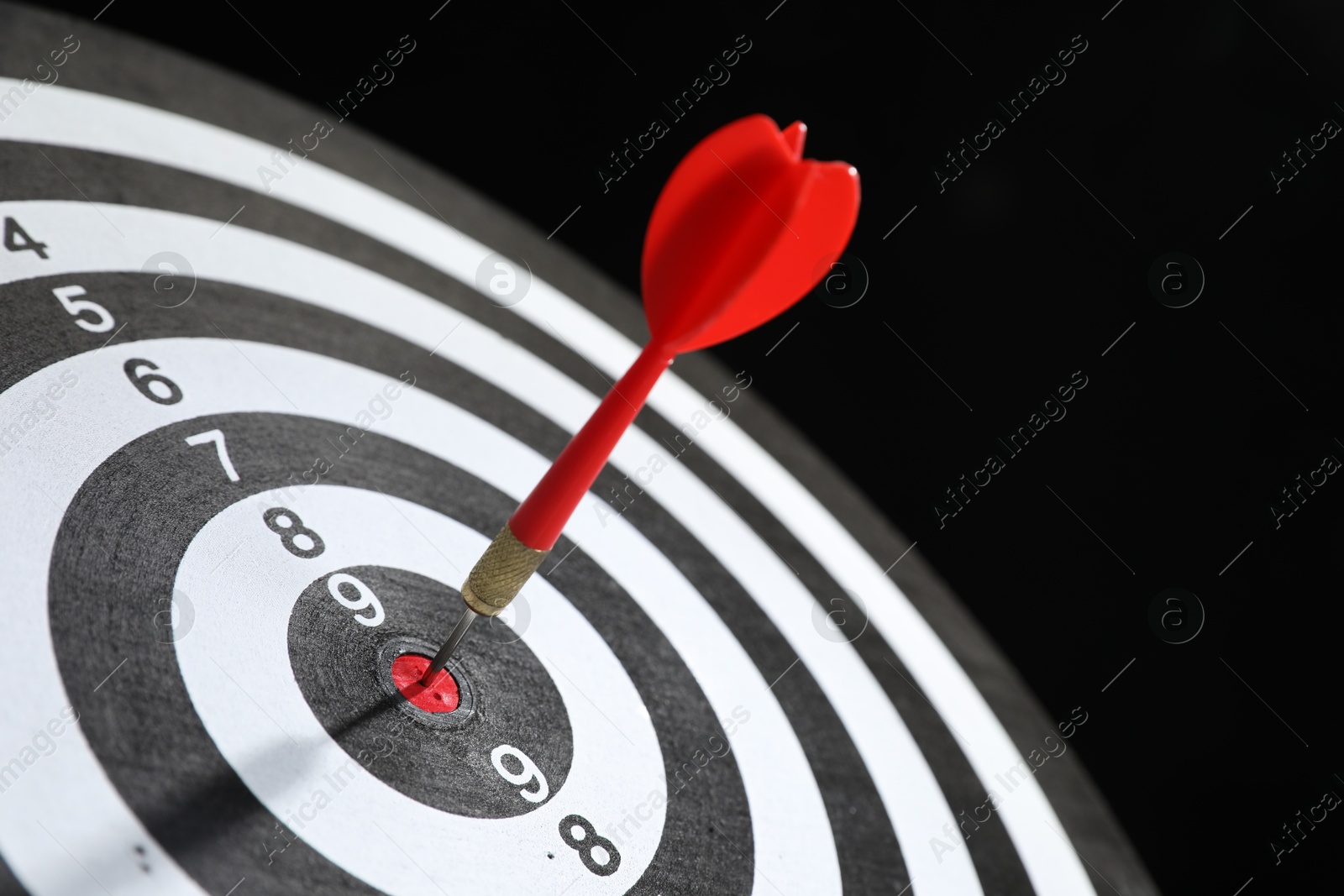 Targeting. Dart board with arrow on black background, closeup Photo of Targeting. Dart board with arrow on black background, closeup