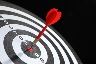Photo of Targeting. Dart board with arrow on black background, closeup