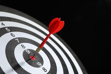 Photo of Targeting. Dart board with arrow on black background, closeup