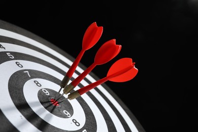 Photo of Targeting. Dart board with arrows on black background, closeup