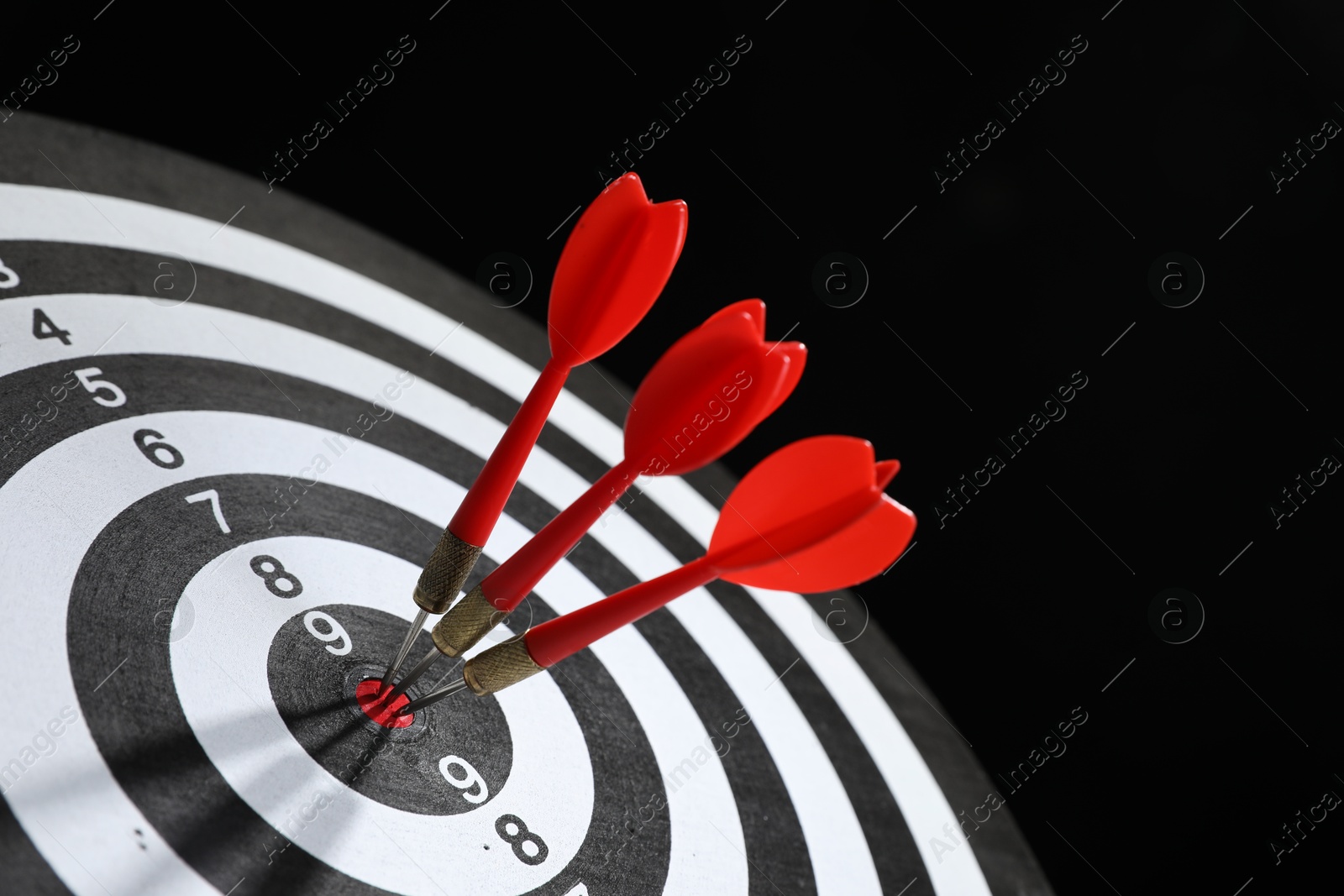 Targeting. Dart board with arrows on black background, closeup Photo of Targeting. Dart board with arrows on black background, closeup