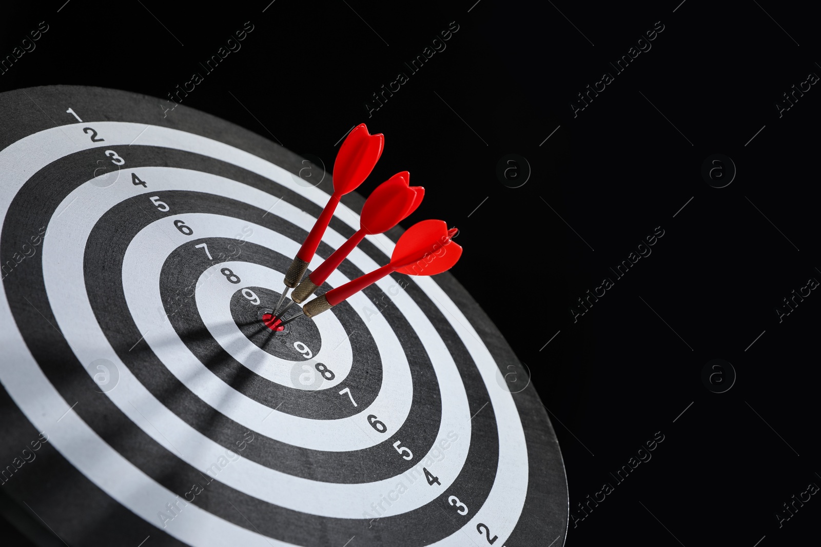 Targeting. Dart board with arrows on black background, closeup. Space for text Photo of Targeting. Dart board with arrows on black background, closeup. Space for text