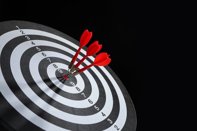 Photo of Targeting. Dart board with arrows on black background, closeup. Space for text