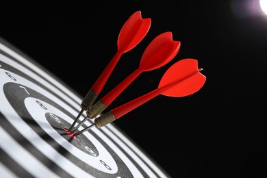 Photo of Targeting. Dart board with arrows on black background, closeup