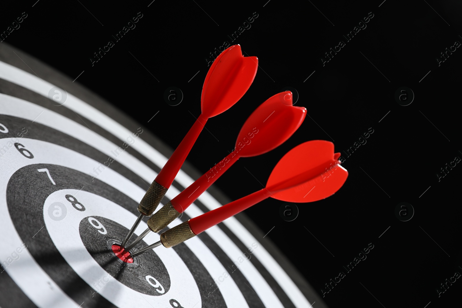 Targeting. Dart board with arrows on black background, closeup Photo of Targeting. Dart board with arrows on black background, closeup