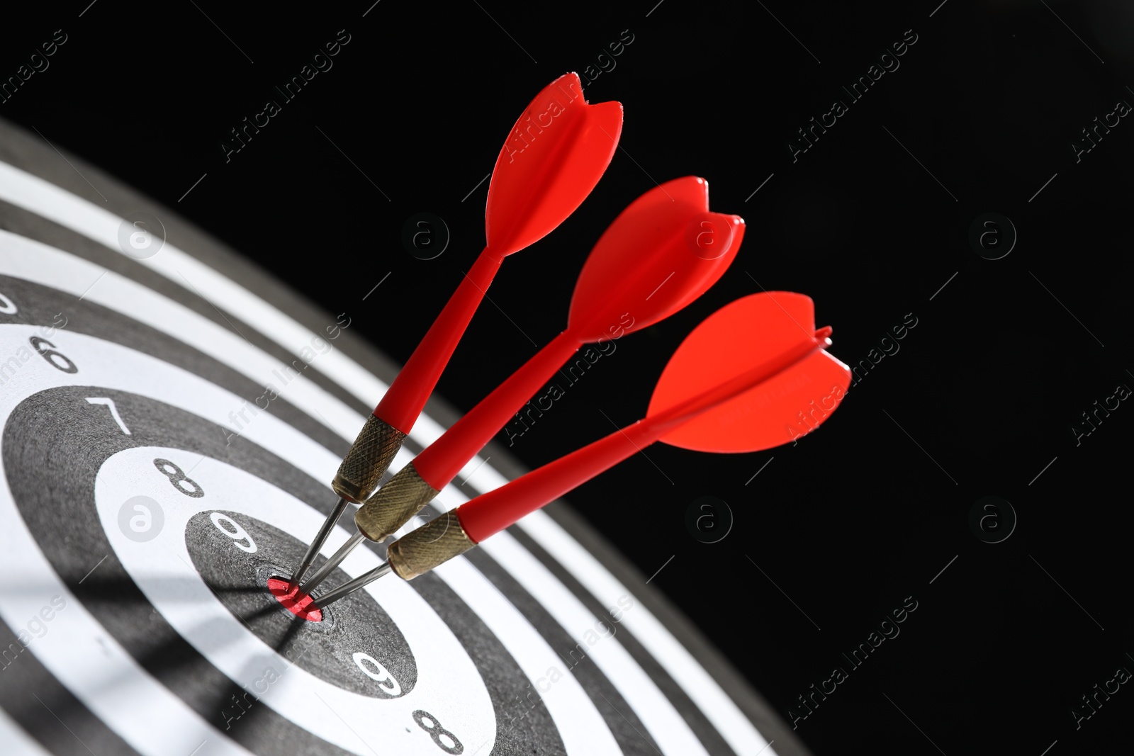 Targeting. Dart board with arrows on black background, closeup Photo of Targeting. Dart board with arrows on black background, closeup