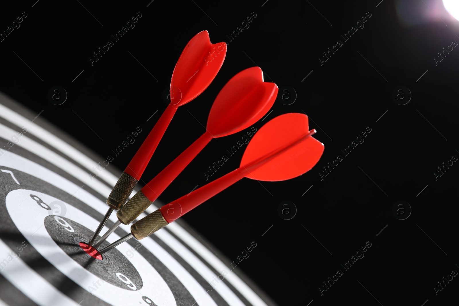 Targeting. Dart board with arrows on black background, closeup Photo of Targeting. Dart board with arrows on black background, closeup