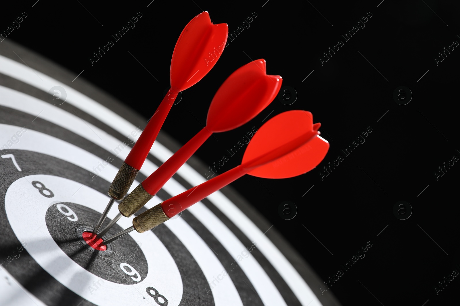 Targeting. Dart board with arrows on black background, closeup Photo of Targeting. Dart board with arrows on black background, closeup