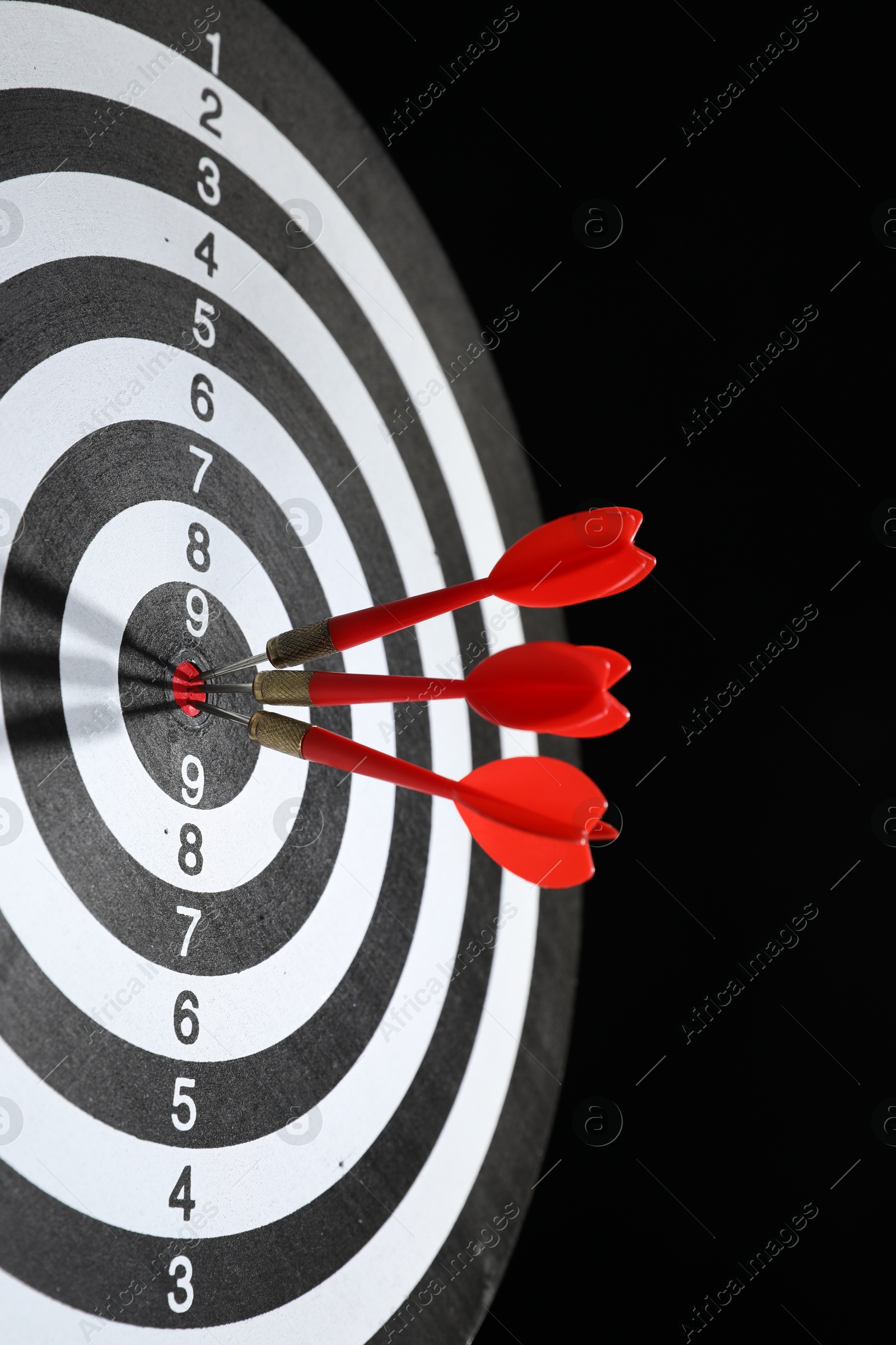 Targeting. Dart board with arrows on black background, closeup Photo of Targeting. Dart board with arrows on black background, closeup