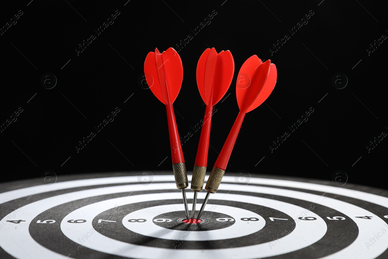 Targeting. Dart board with arrows on black background, closeup Photo of Targeting. Dart board with arrows on black background, closeup