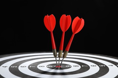 Photo of Targeting. Dart board with arrows on black background, closeup