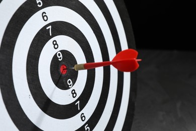 Photo of Targeting. Dart board with arrow on dark background, closeup