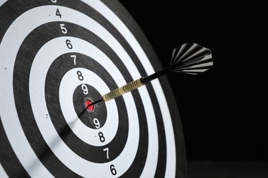 Photo of Targeting. Dart board with arrow on dark background, closeup