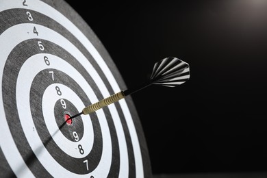 Photo of Targeting. Dart board with arrow on dark background, closeup