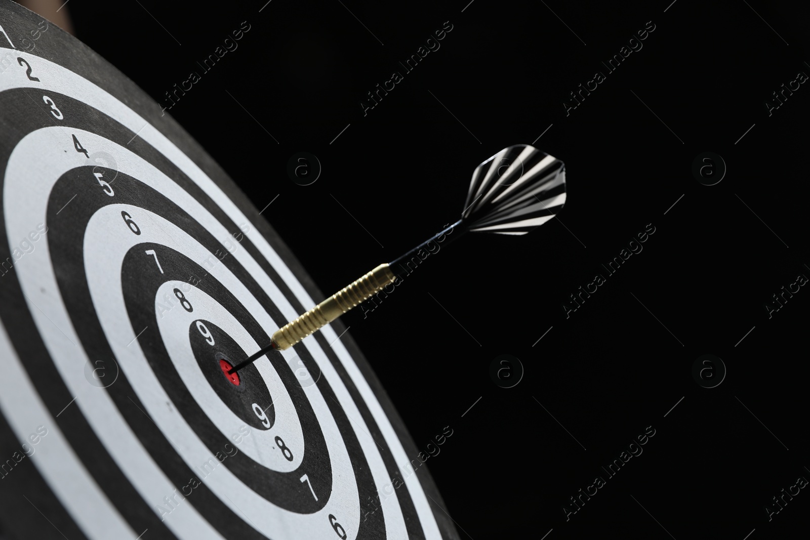 Targeting. Dart board with arrow on black background, closeup Photo of Targeting. Dart board with arrow on black background, closeup