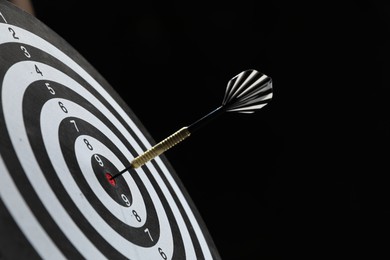 Photo of Targeting. Dart board with arrow on black background, closeup